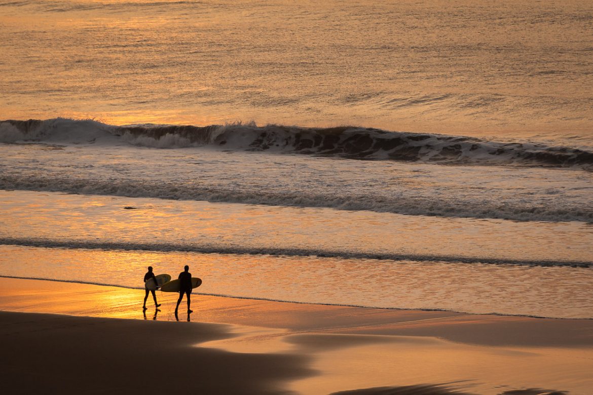 Surfers head out to the waves at Welcombe Mouth beach in Devon